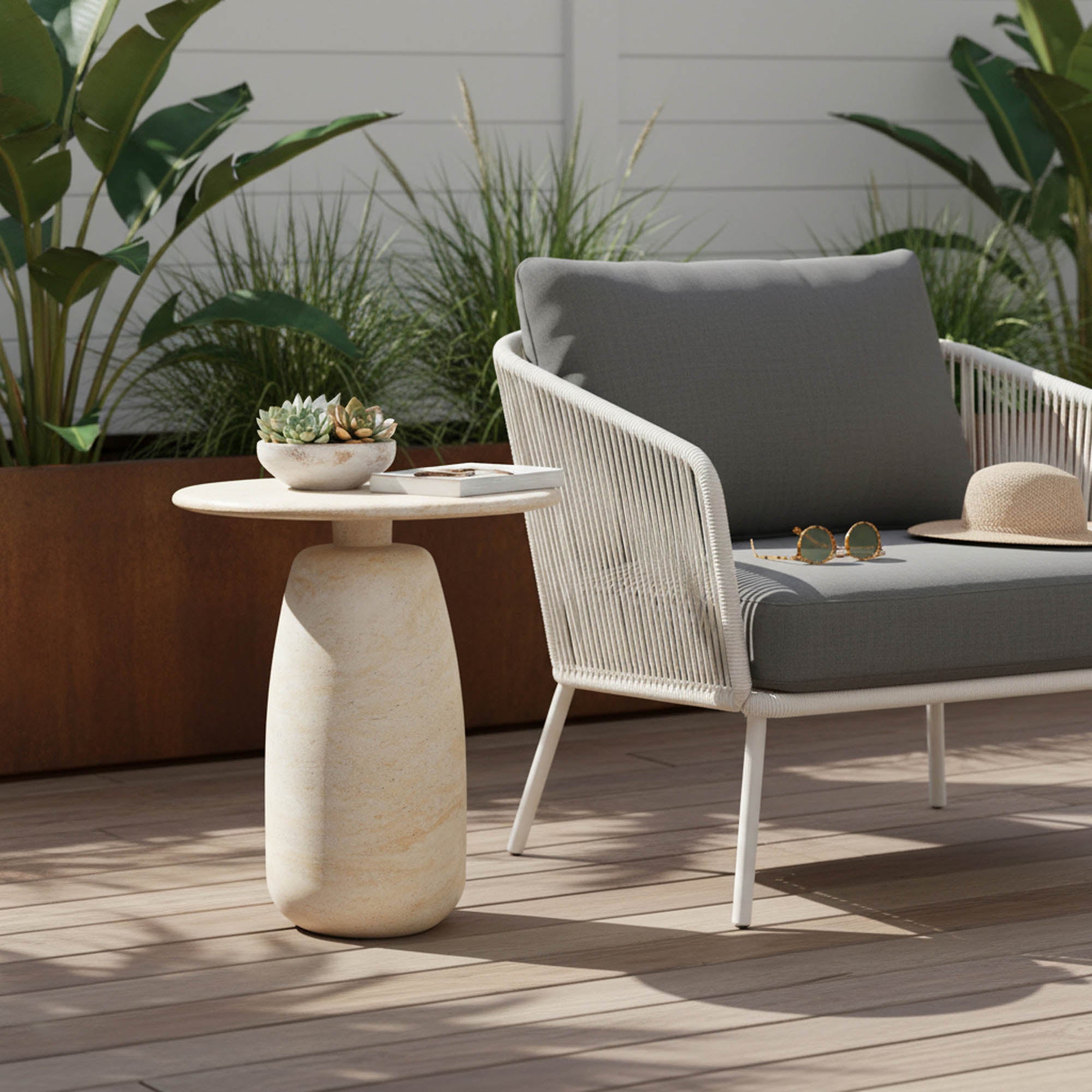 Olympia Side Table Tall styled on a wood-deck outdoor patio alongside a cushioned rope lounge chair, with tropical plants in the background